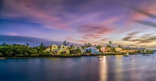 Buildings by sea against sky during sunset