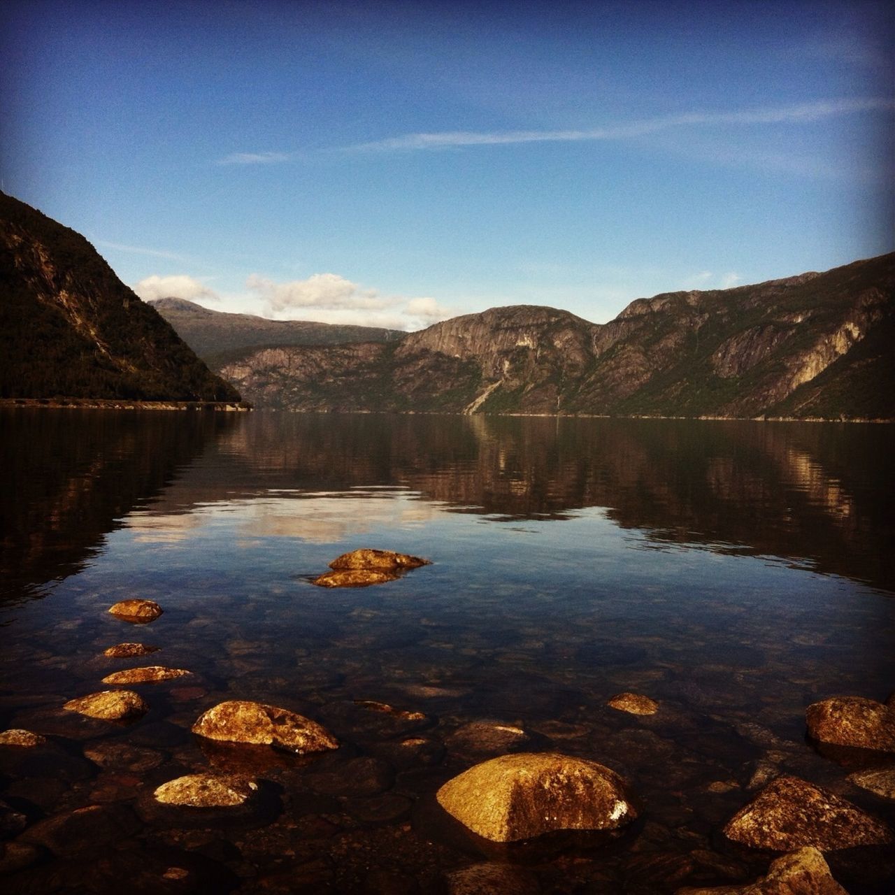 water, lake, tranquil scene, tranquility, reflection, mountain, scenics, beauty in nature, sky, nature, mountain range, idyllic, rock - object, non-urban scene, lakeshore, landscape, calm, countryside, river, day