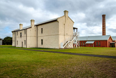 Houses on grassy field against cloudy sky