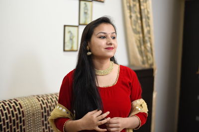 Beautiful young woman looking away while standing against wall