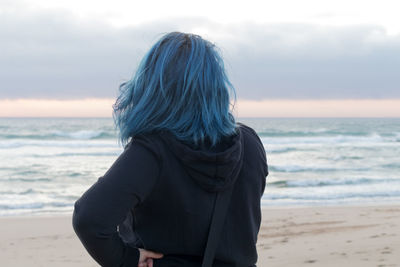 Rear view of woman standing on beach against sky