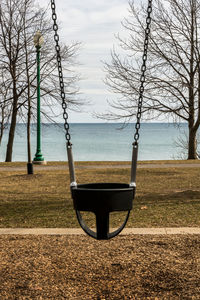 Empty child's chain swing with the view of a lake and the  change of season.