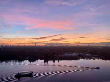 A small boat sets off at sunrise on the chao phraya river, bangkok, under a stunning sky