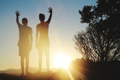 Silhouette men standing on field against sky during sunset