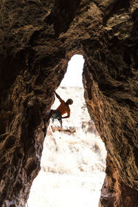 Hiker climbing rock formation at desert