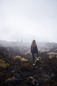 Rear view of woman standing on land against sky