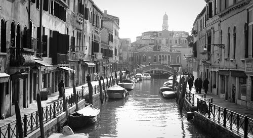 Boats moored in canal amidst buildings in city