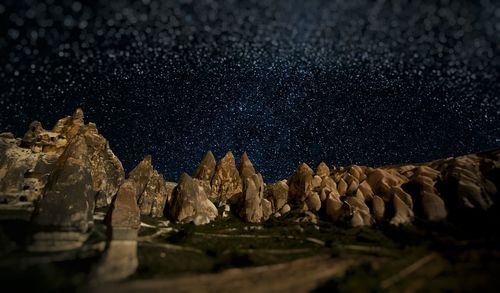 Standing rocks on landscape against starry sky