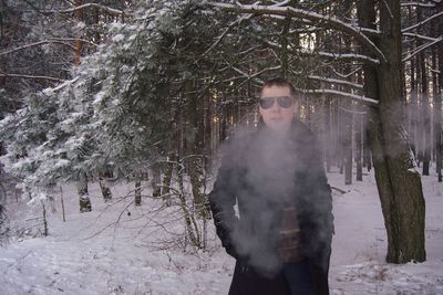 Portrait of man standing in snow covered forest