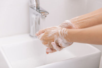 Cropped hand washing hands in sink