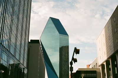 Low angle view of skyscrapers against cloudy sky