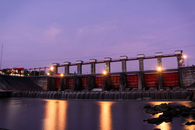 Illuminated bridge over river against sky at night