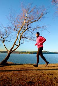 Runner in pink jacket runs along coastline. sport and jogging cross country training workout