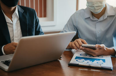 Midsection of man using laptop on table