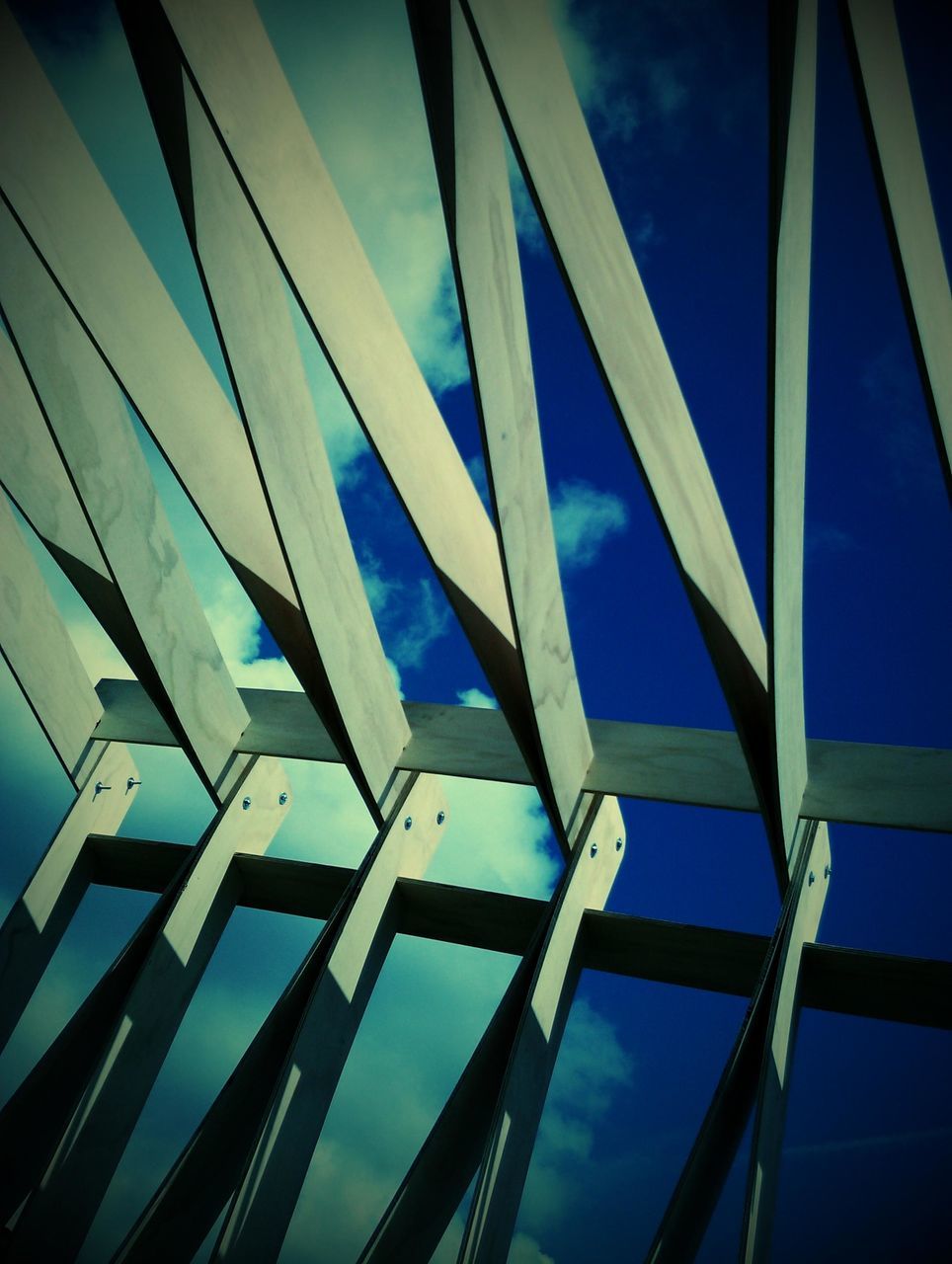 low angle view, blue, built structure, architecture, sky, modern, metal, pattern, railing, no people, day, outdoors, building exterior, sunlight, building, part of, glass - material, repetition, metallic