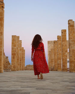 Rear view of woman walking against buildings in city