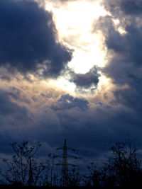 Low angle view of bare trees against cloudy sky