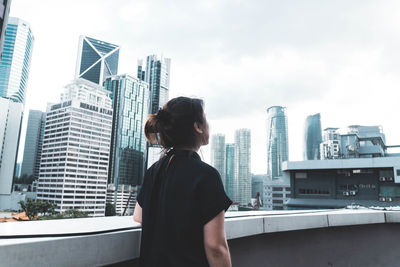 Woman standing against modern buildings in city