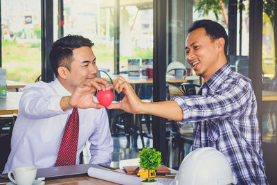 Smiling businessmen holding heart shape in office