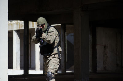 Soldier aiming with machine gun while standing in building
