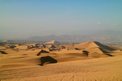 Golden sand dunes with the wheel prints of dune buggies, huacachina, ica, peru