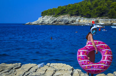 Woman with inflatable ring standing at beach