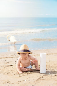 Cute baby boy playing at sandy beach during sunny day