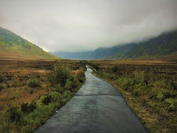 Road leading towards mountains against sky