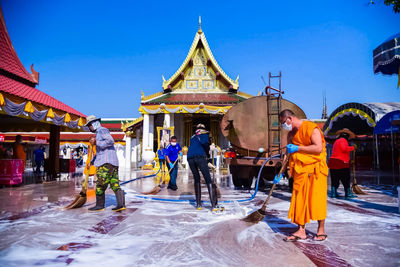 People walking outside temple against building