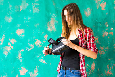 Woman holding umbrella standing against graffiti wall