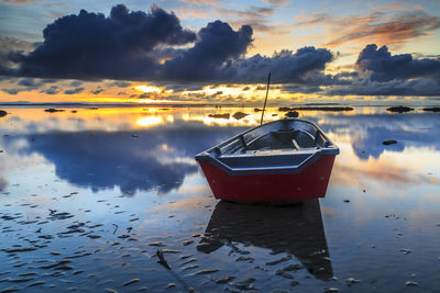 Boat moored in sea against sky during sunset