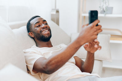 Young man using mobile phone while lying on bed at home