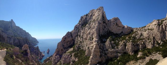 Panoramic view of rocks and sea against clear blue sky