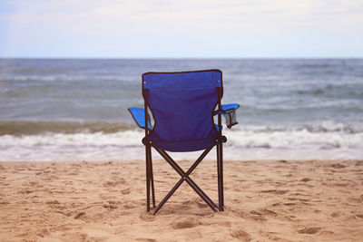 Blue folding chair back on seashore, sea background. blue chair on sea beach, without people. beach