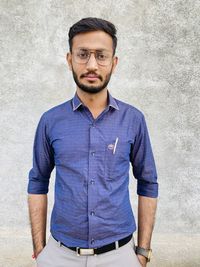 Portrait of young man standing against wall