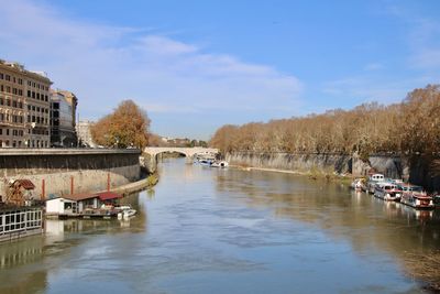 Scenic view of river by buildings against sky