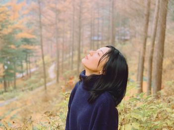 Young woman wearing sweater standing in forest during autumn