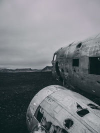 Abandoned airplane on sea shore against sky