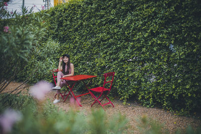 Woman sitting on plants against trees