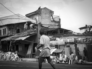 Man walking on street by incomplete building