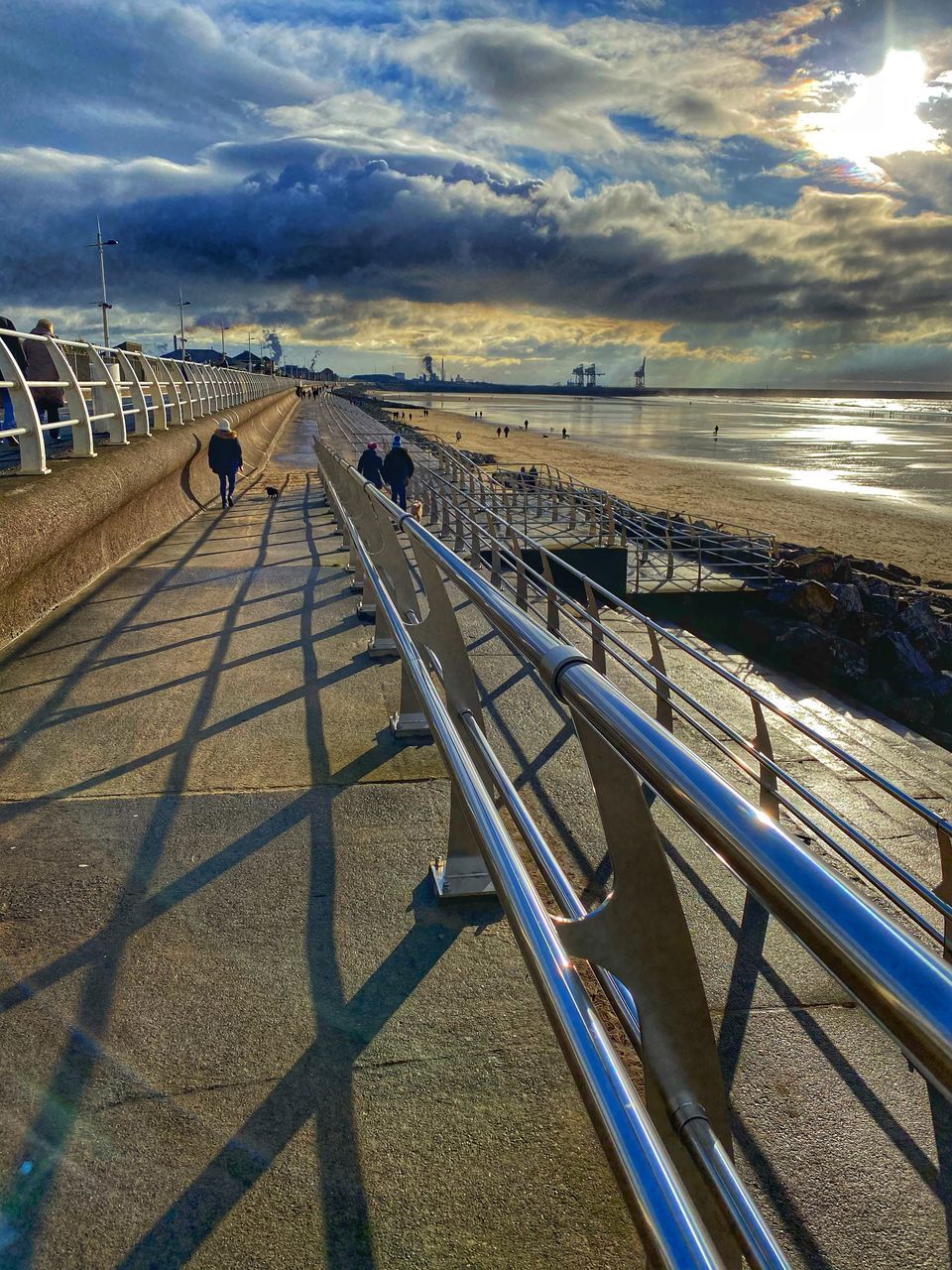 sky, nature, cloud, water, sea, sunlight, coast, transportation, railing, horizon, reflection, beach, land, shadow, pier, sunset, scenics - nature, beauty in nature, blue, outdoors, ocean, walkway, architecture, travel, day, no people, shore, mode of transportation, travel destinations, the way forward, tranquility, built structure