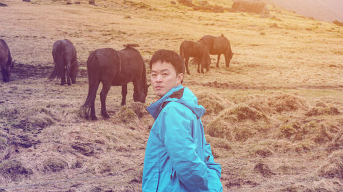 Portrait of man with horses grazing on grass