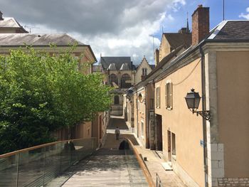 Mid distance of man walking on footpath amidst buildings in city against sky