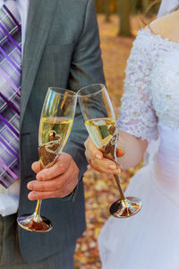 Midsection of bride and bridegroom toasting champagne flutes