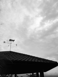 Low angle view of weather vane against cloudy sky