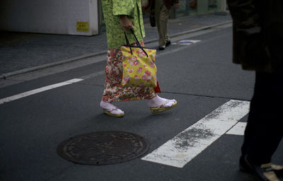 Low section of woman walking on sidewalk