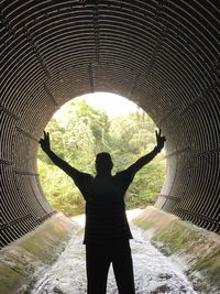 Rear view of silhouette man standing in tunnel