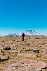 Full length of man climbing on mountain against clear blue sky
