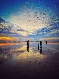 People on sea against sky during sunset