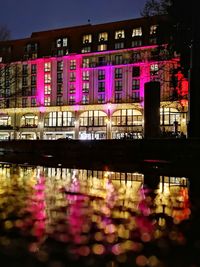 Illuminated bridge over river in city at night